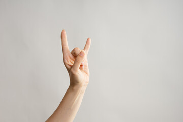 Hand gestures, Thumbs up, that's a cool gesture of the rocker. women's hand. light grey background
