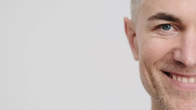 A close-up view of a half face of a doctor man wearing is smiling to the camera isolated over grey background in the studio