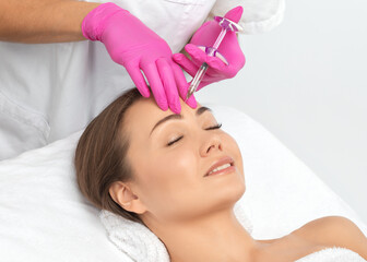 Cosmetologist makes rejuvenating anti wrinkle injections on the face of a beautiful woman. Female...