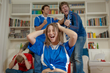 Ragazzi esultano per un gol mentre guardano la partita di calcio in televisione in casa