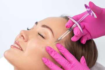 Cosmetologist makes rejuvenating anti wrinkle injections on the face of a beautiful woman. Female...