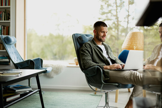Smiling man using laptop in living room