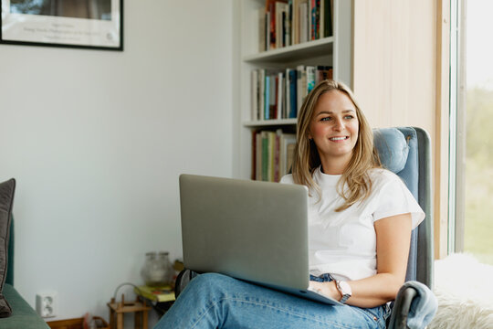 Smiling woman using laptop in living room