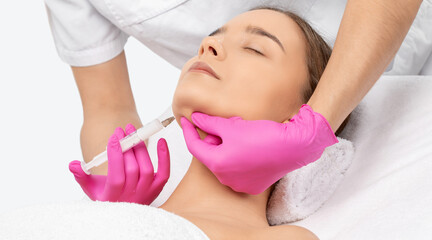 Cosmetologist makes lipolytic injections to burn fat on the chin, cheeks and neck of a woman...