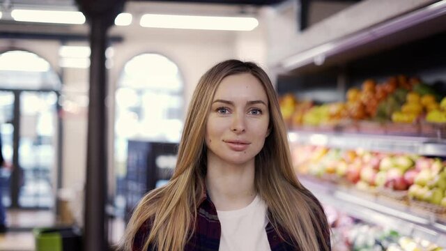 Confident girl walking by supermarket through fruits aisle