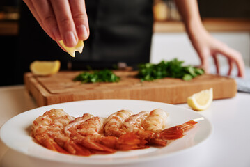 Cooking prawns. Chef pour lemon juice on shrimps