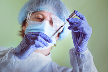 Vaccination, doctor in protective clothes with syringe and ampule