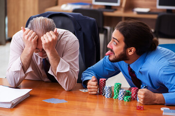 Two male employees playing cards at workplace