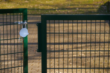 corona mask hanging at half open fence door symbolising death by covid19
