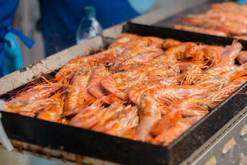 Process of cooking fresh red langoustine shrimps, prawns on grill at summer local food market - close up. Outdoor cooking, barbecue, gastronomy, seafood, cookery, street food concept