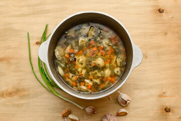 cauldron of soup and garlic on wooden background, home cooking
