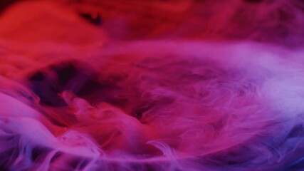 Vibrating bass speaker with curling colorful red, purple and blue smoke, slow motion shot
