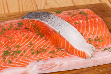 Slice of raw salmon on salmon fillet on cutting board
