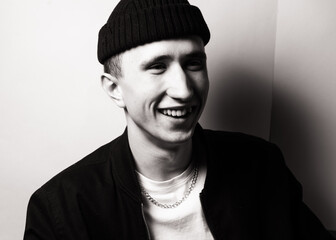 portrait of smiling young  man  wearing black knit hat. Black and white studio shot on white background. Teenagerhood.