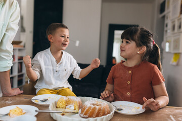 mother and her children enjoying time together. they eating cake at home