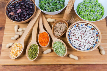 Various dry and frozen legumes in bowls and wooden spoons