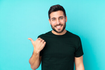 Fototapeta premium Caucasian handsome man isolated on blue background pointing to the side to present a product