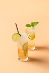 Refreshing orange two lemonade sodas with lime slice on color background. Summer fresh drink.