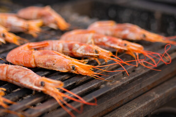 Close up - process of cooking fresh red langoustine shrimps, prawns on grill at summer local food market. Outdoor cooking, barbecue, gastronomy, seafood, cookery, street food concept