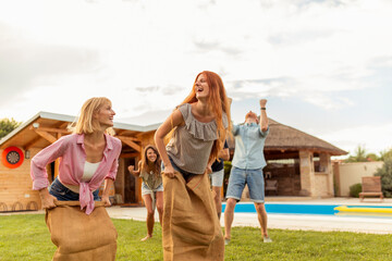 Friends having a jumping sack race in the backyard