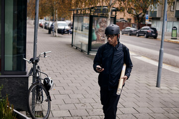 Bicycle courier on sidewalk using cell phone