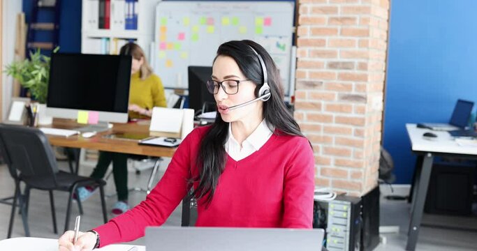 Woman in headphones speaking into microphone at workplace 4k movie. Work in call center concept
