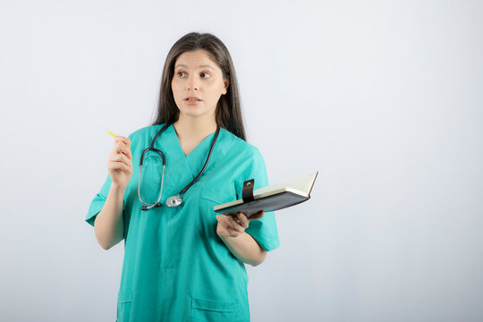Photo of a young female doctor standing with notebook and pencil