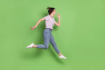 Fototapeta na wymiar Full length body size profile side view of pretty cheerful girl jumping running isolated over green pastel color background