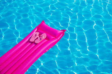Beach summer holiday background. Inflatable air mattress, flip flops on swimming pool.