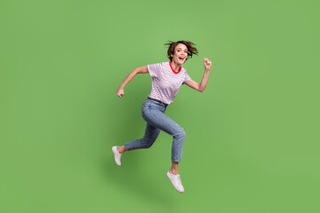 Full length body size profile side view of lovely cheerful girl jumping running action isolated over green pastel color background