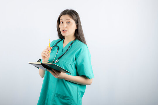 Photo of a young female doctor standing with notebook and pencil