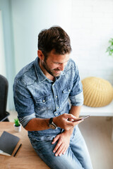 Businessman in office using the phone. Young man typing a message..