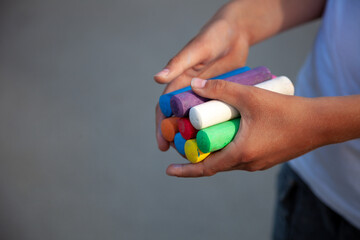 Chalks. Large multi-colored crayons in children's hands. The child holds the chalk. Draw on the street. Fascinating drawing for children