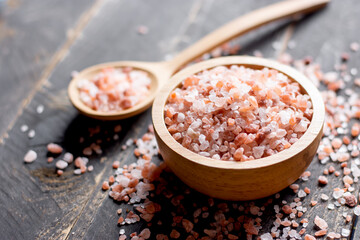 Fototapeta na wymiar Pink salt in a wooden bowl, placed on a black wood, Himalayan salt.