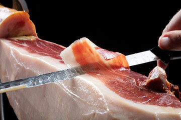 jamón serrano iberico de bellota cortado con cuchillo, mano, vista cenital. Acorn-fed Iberian...