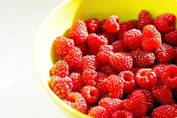 Close-up of ripe raspberry fruits on a bamboo plate on the table.
