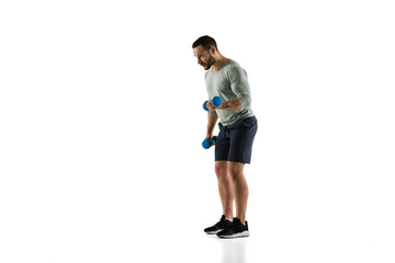 Dumbbells. Young caucasian male model in action, motion on white background with copyspace. Concept of sport, movement, energy and dynamic, healthy lifestyle. Training, practicing. Authentic.