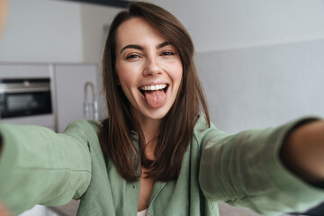 Happy blonde woman showing her tongue while taking selfie photo