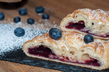 Pastry rolls with blueberries, powdered sugar on top, tasty delicious pastry buns freshly baked, close-up view.