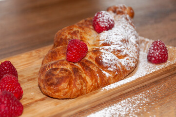 Pastry rolls with raspberries, powdered sugar on top, tasty delicious pastry buns freshly baked, close-up view.