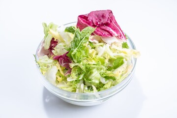 Lettuce salad in transparent bowl isolated on white.  View from above.