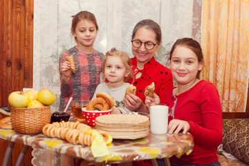 Senior woman with granddaughters at  table with  stack of pancakes and tea