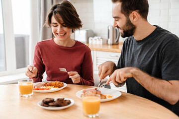 Cheerful attractive young couple having tasty breakfast