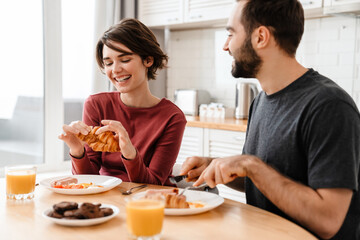 Obraz na płótnie Canvas Cheerful attractive young couple having tasty breakfast