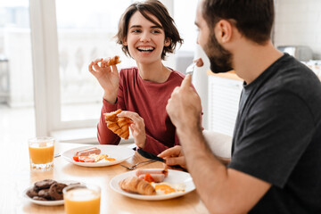 Cheerful attractive young couple having tasty breakfast