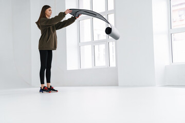 Athletic pleased sportswoman unrolling fitness mat before practice