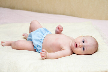 A 5 month old baby lies on a pink blanket. Happy young child.