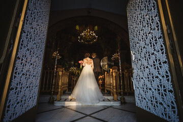 Bride and groom entering in a church in wedding dress