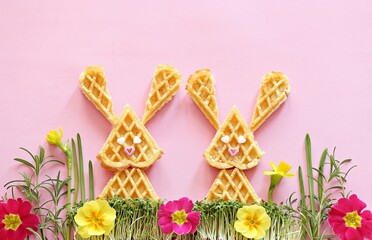 Waffles in the shape of an Easter bunny on a decorative meadow. Flat layot, copy space
