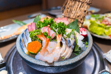 Close-up of Japanese sushi and sashimi food. Maki ands rolls with tuna, salmon, and fish egg. Top view of assorted sushi. Side view of assorted sashimi with tuna, salmon, shrimp, fish egg. 